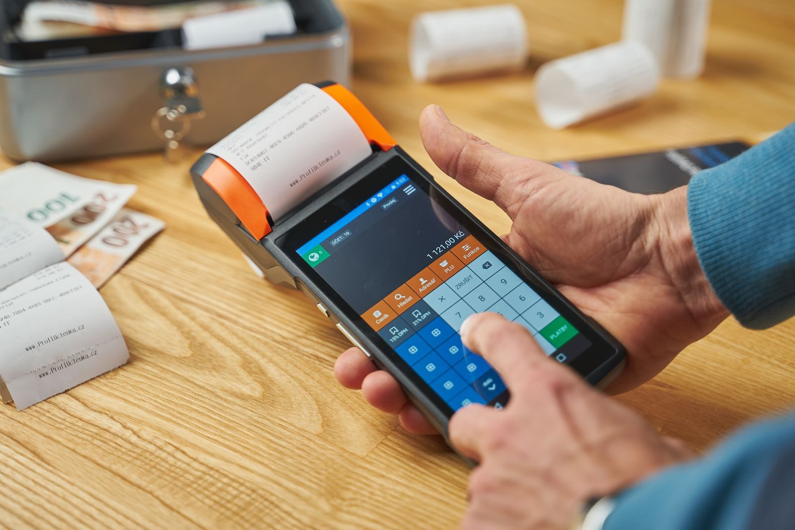 Close-up of hands operating a modern point of sale device with a printed receipt.