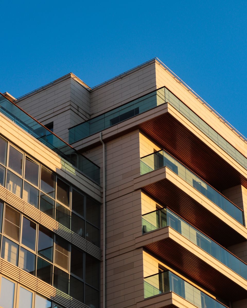 A modern building with glass balconies highlighted by warm sunlight under a clear blue sky.