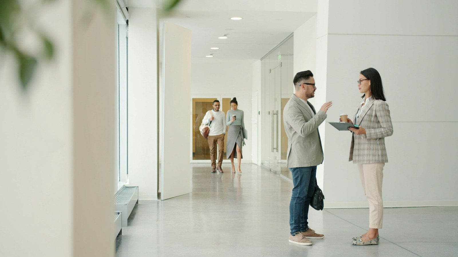 Two people talking in a modern office hallway